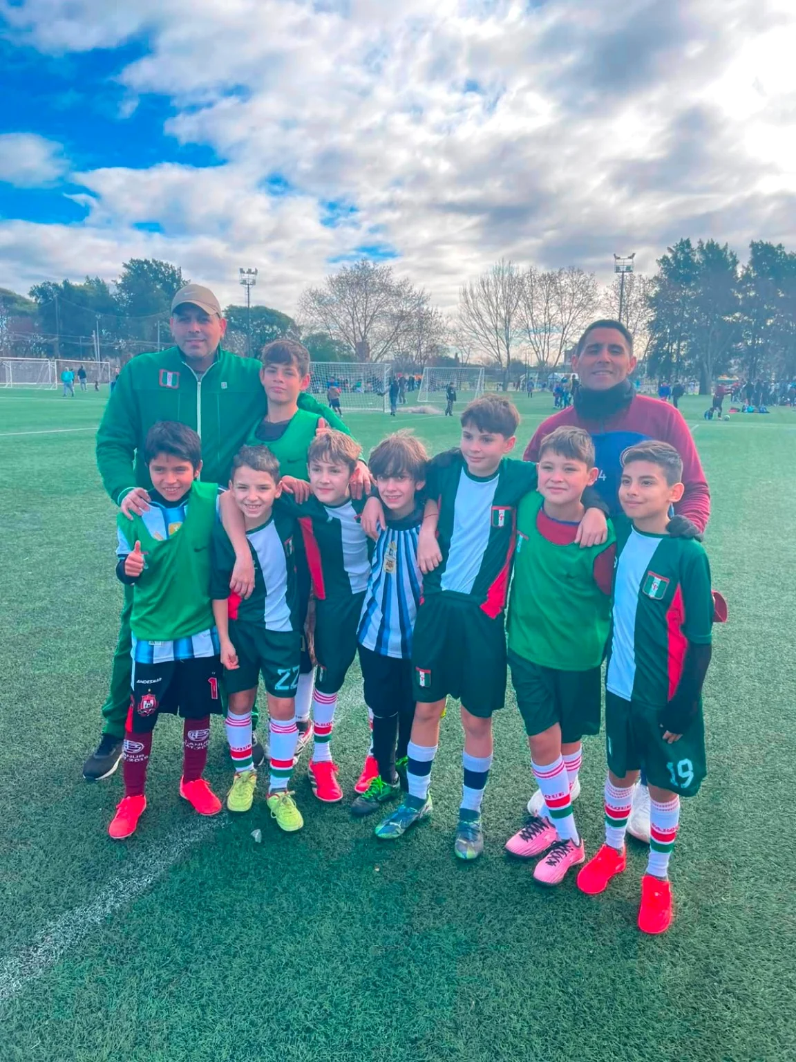 Marcelo Prahim junto a un grupo de jugadores infantiles en una cancha de fútbol